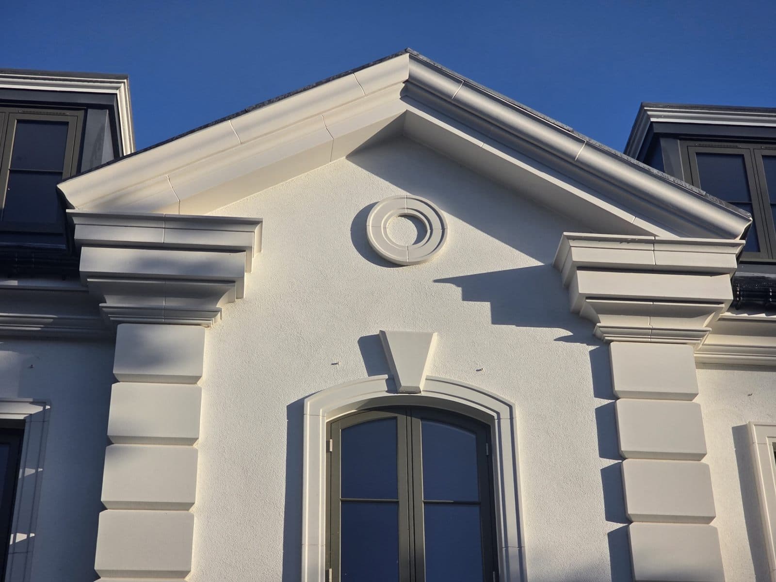 Pediment, oculus, pilaster capitals and arched window surround