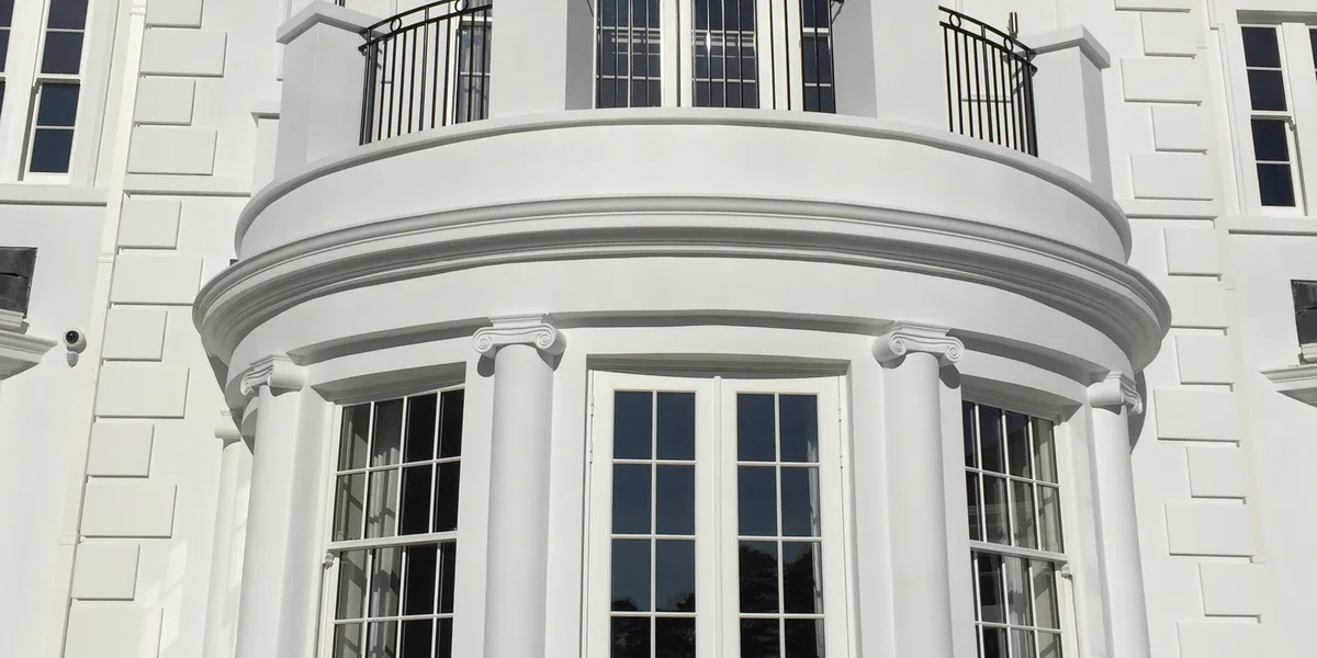 Curved cornice and columns around a round bay on a white residence