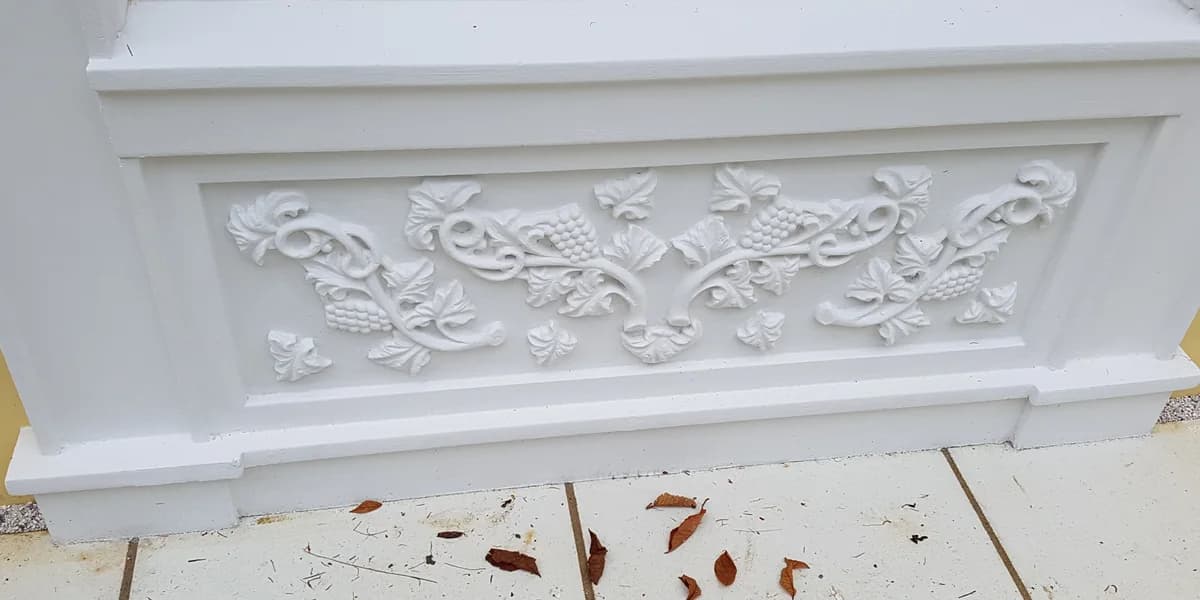 Decorative relief panel with leaves and scrollwork beneath a window
