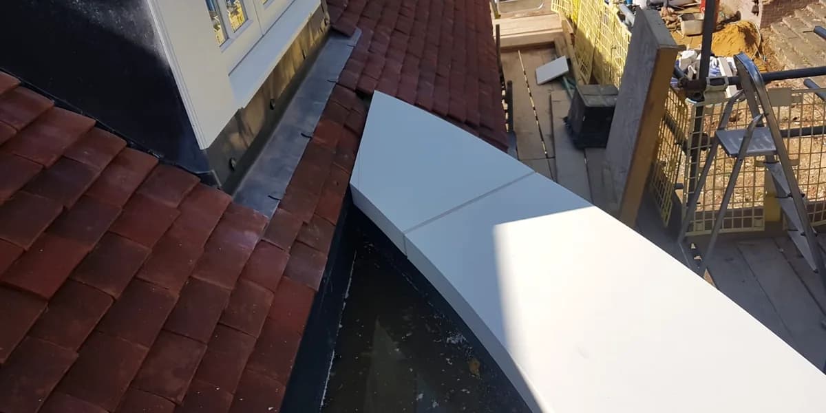 Profiled parapet coping meeting a pitched tiled roof beside a dormer