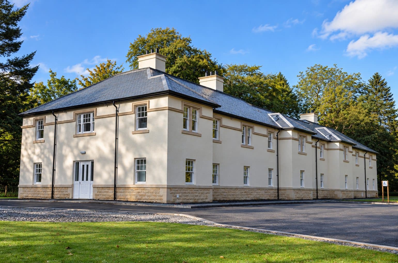 Finished external wall insulation with cream render and stone base on a two-storey building