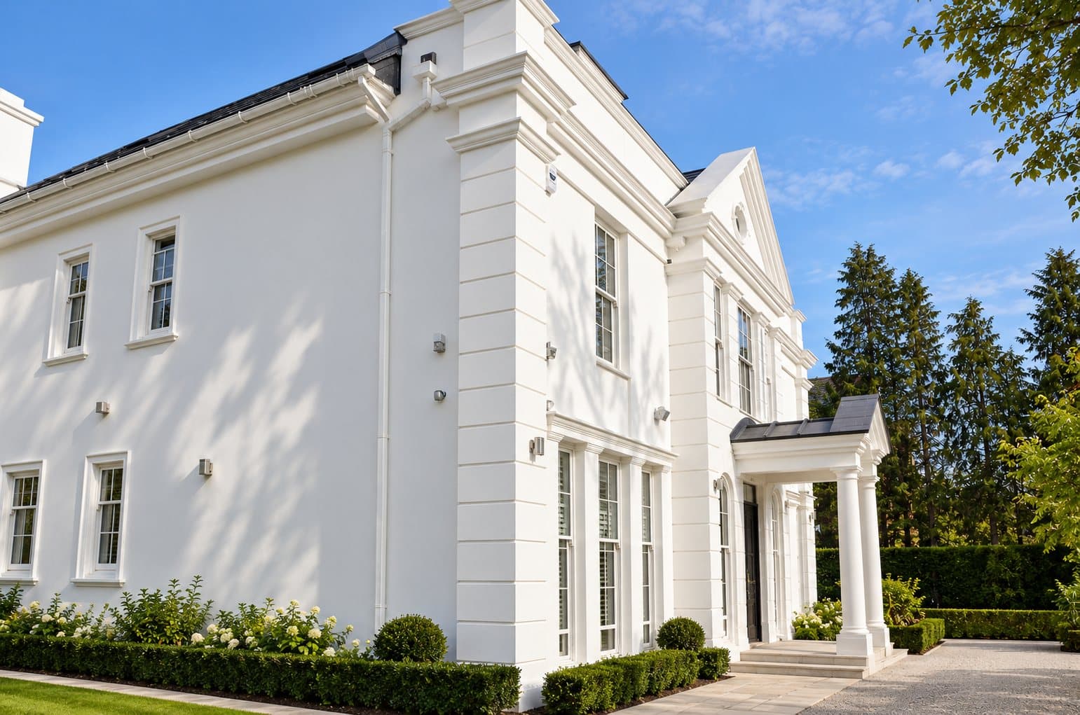 White rendered house with quoins, window surrounds, cornice, pediment and portico