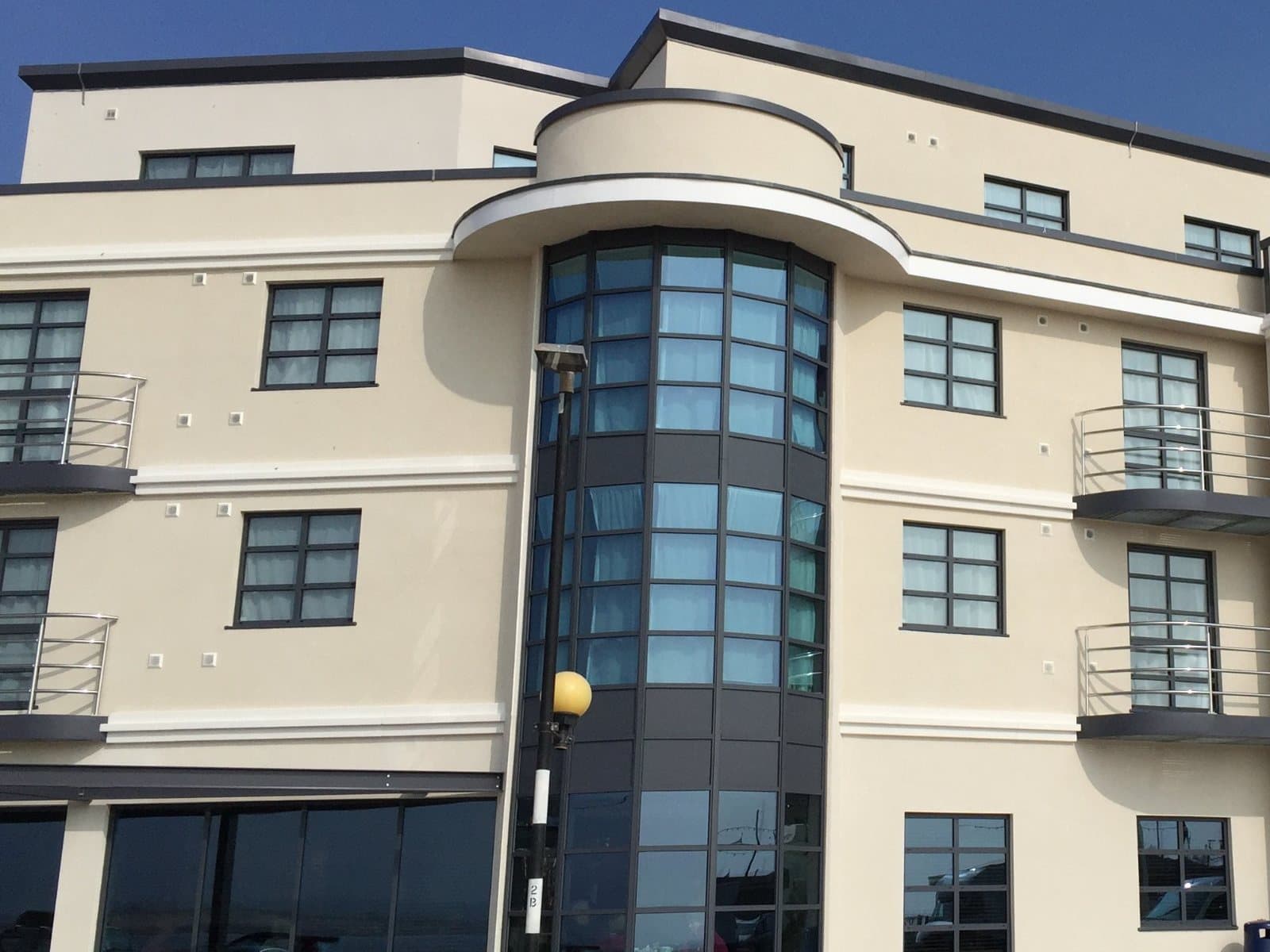 Cream monocouche render with curved glazed bays and white bands