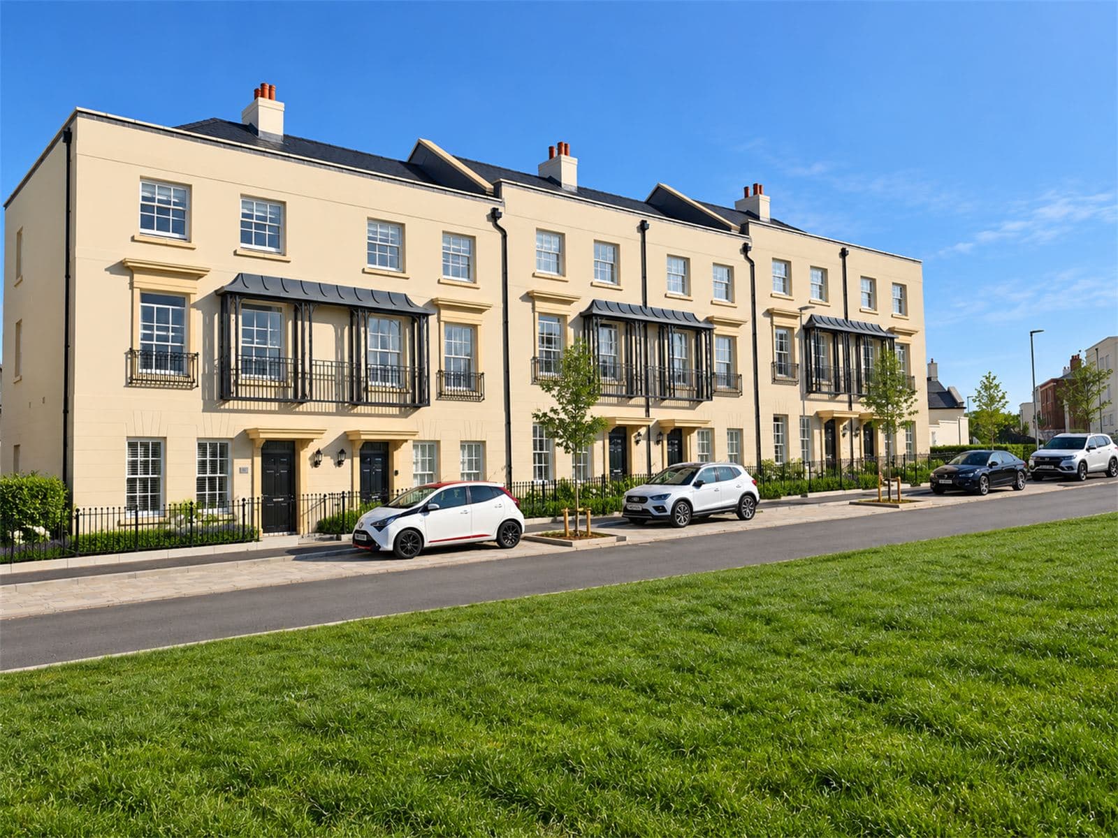 Row of cream rendered townhouses with window heads, canopied balconies and railings