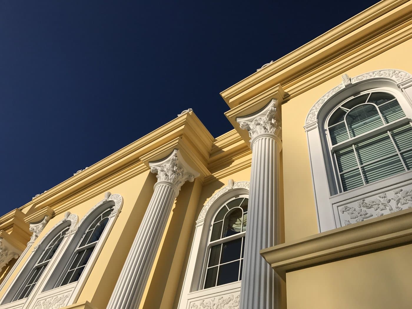 Corinthian capitals beneath projecting cornices beside arched window surrounds at the Surrey residence.
